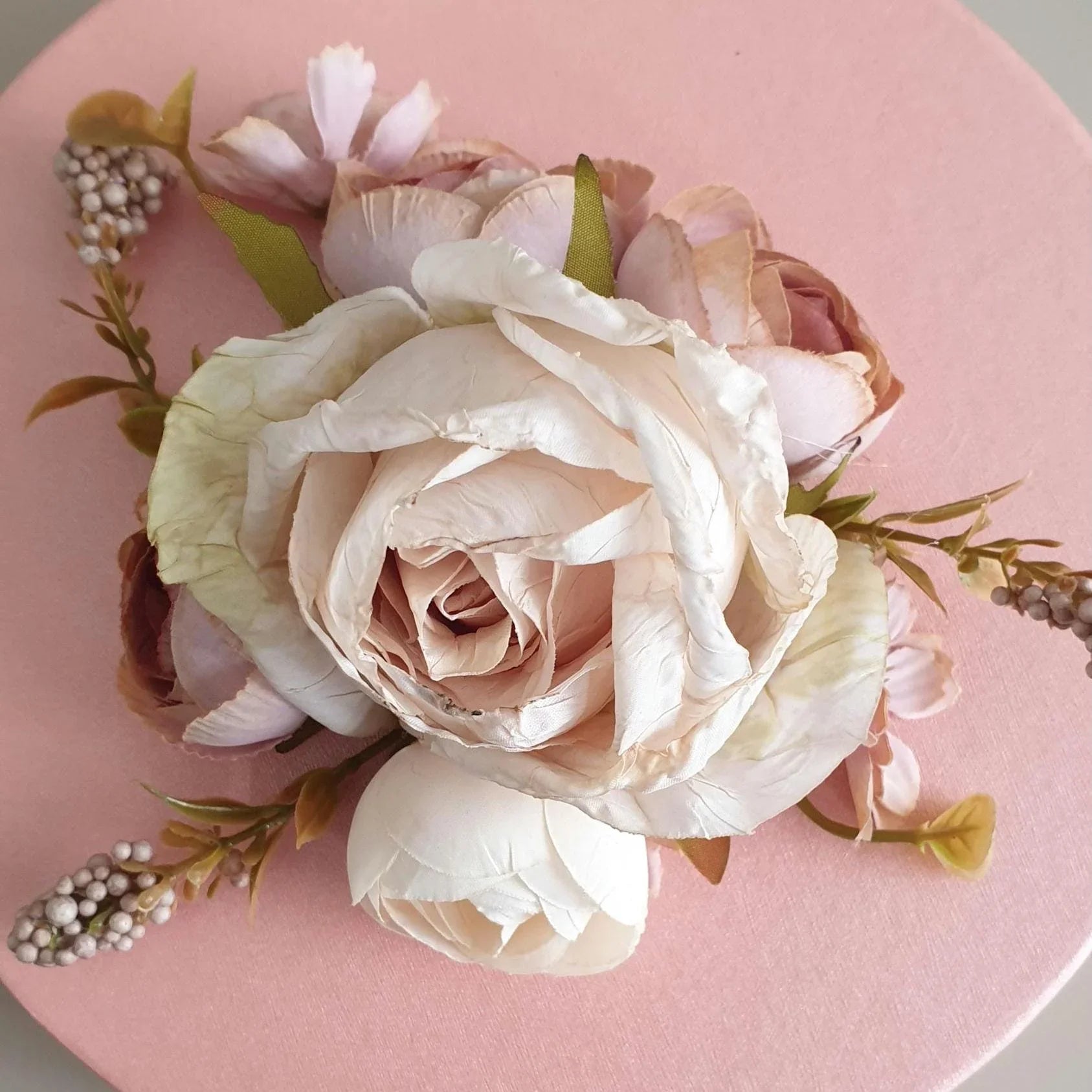 White roses and greenery on a pink plate