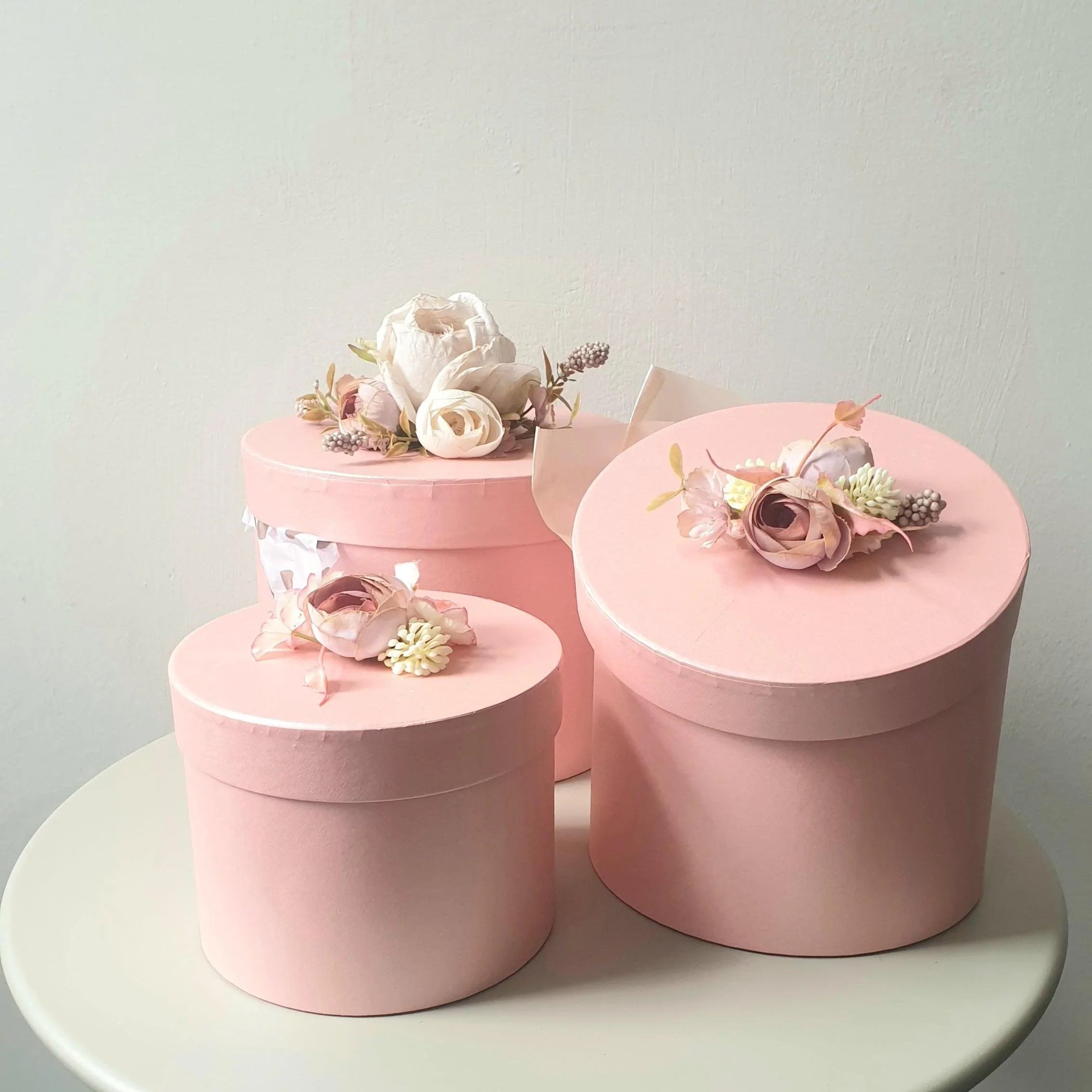 Set of pink decorative boxes with floral arrangements on a light gray background