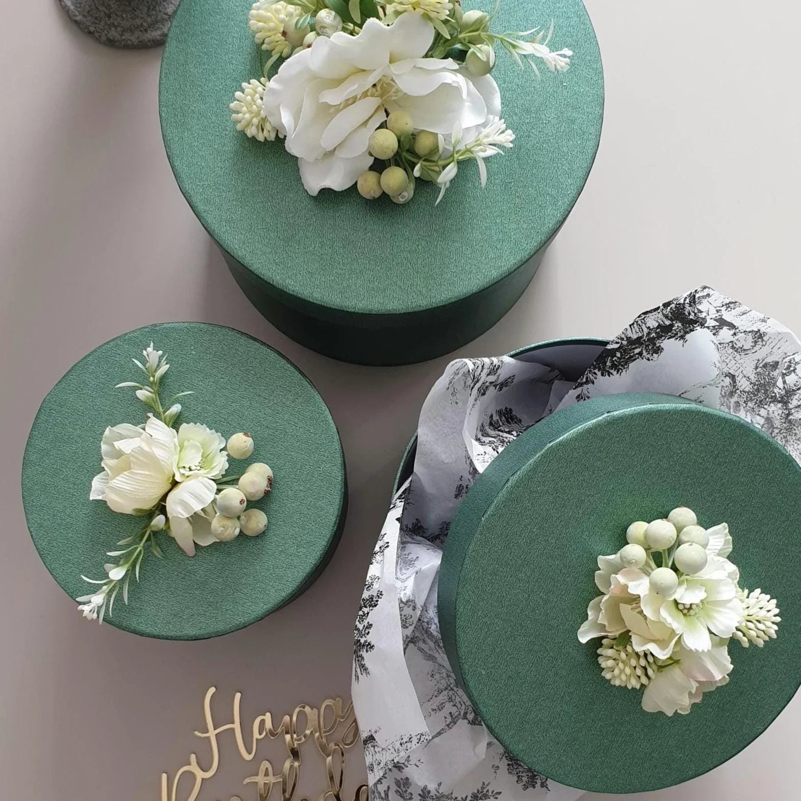 Three green boxes with floral decorations on a light background