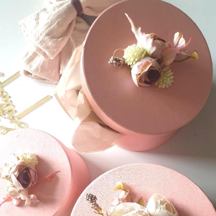 Three pink decorative boxes with floral arrangements on a light background