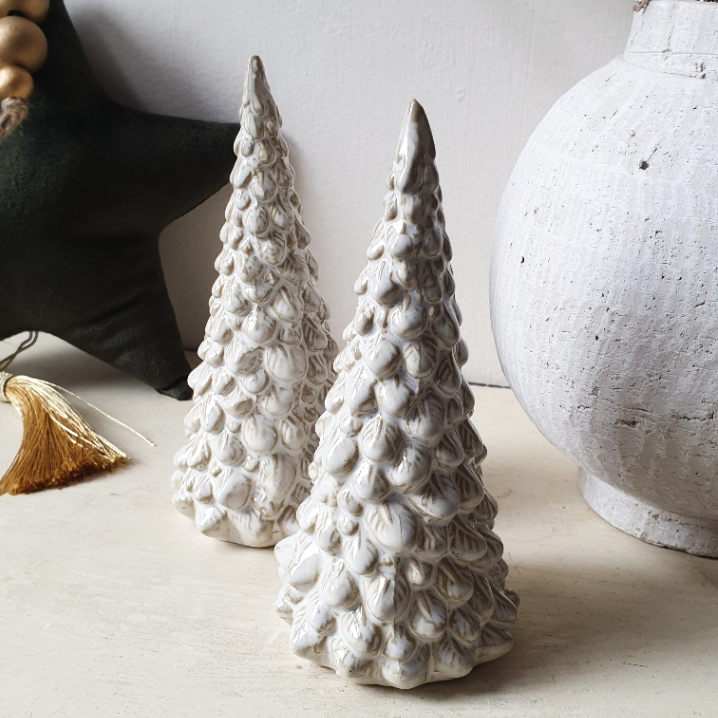 artificial wedding flowers - Two textured ceramic Christmas trees on a neutral surface with decorative items.