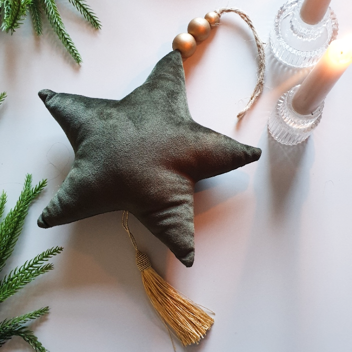artificial wedding flowers - Green star-shaped ornament with a tassel on a light surface with greenery.