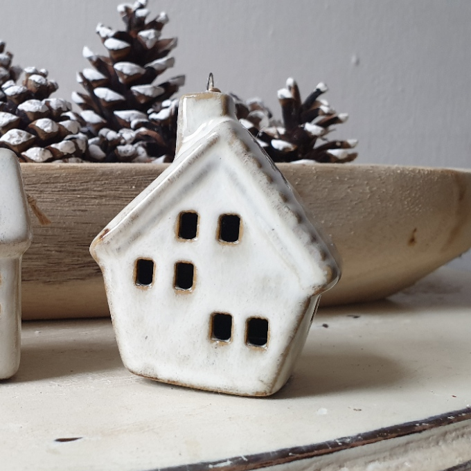 artificial wedding flowers - White ceramic house-shaped ornament with pinecones in the background