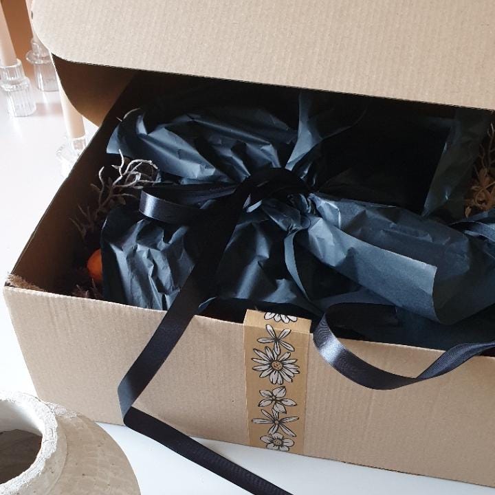 artificial wedding flowers - Gift box with black ribbon and decorative label on a white surface