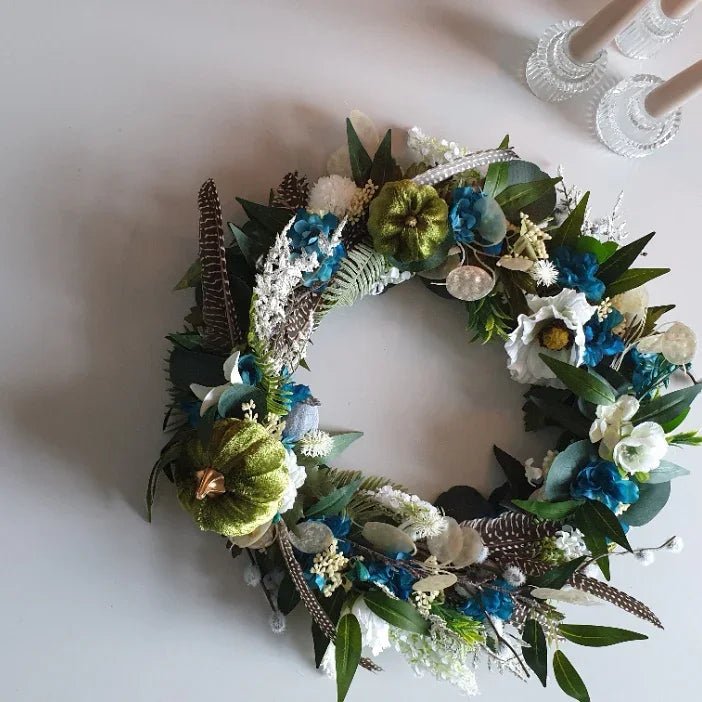 Decorative floral door wreath Cheshire with green, blue, and white flowers on a white background
