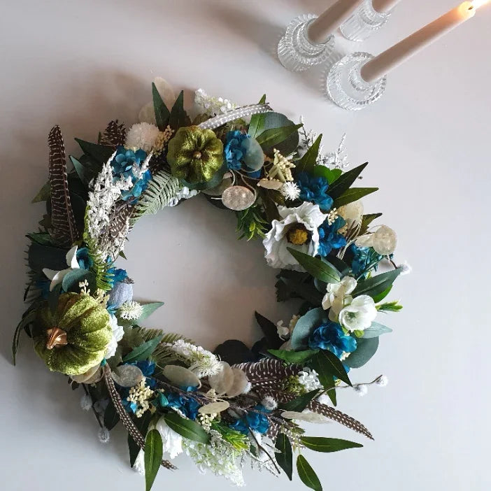 Decorative door wreath Cheshire with green, blue, and white flowers on a light background