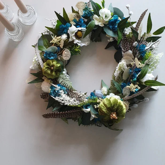 Decorative autumn door wreath Cheshire with green, blue, and white flowers on a white background