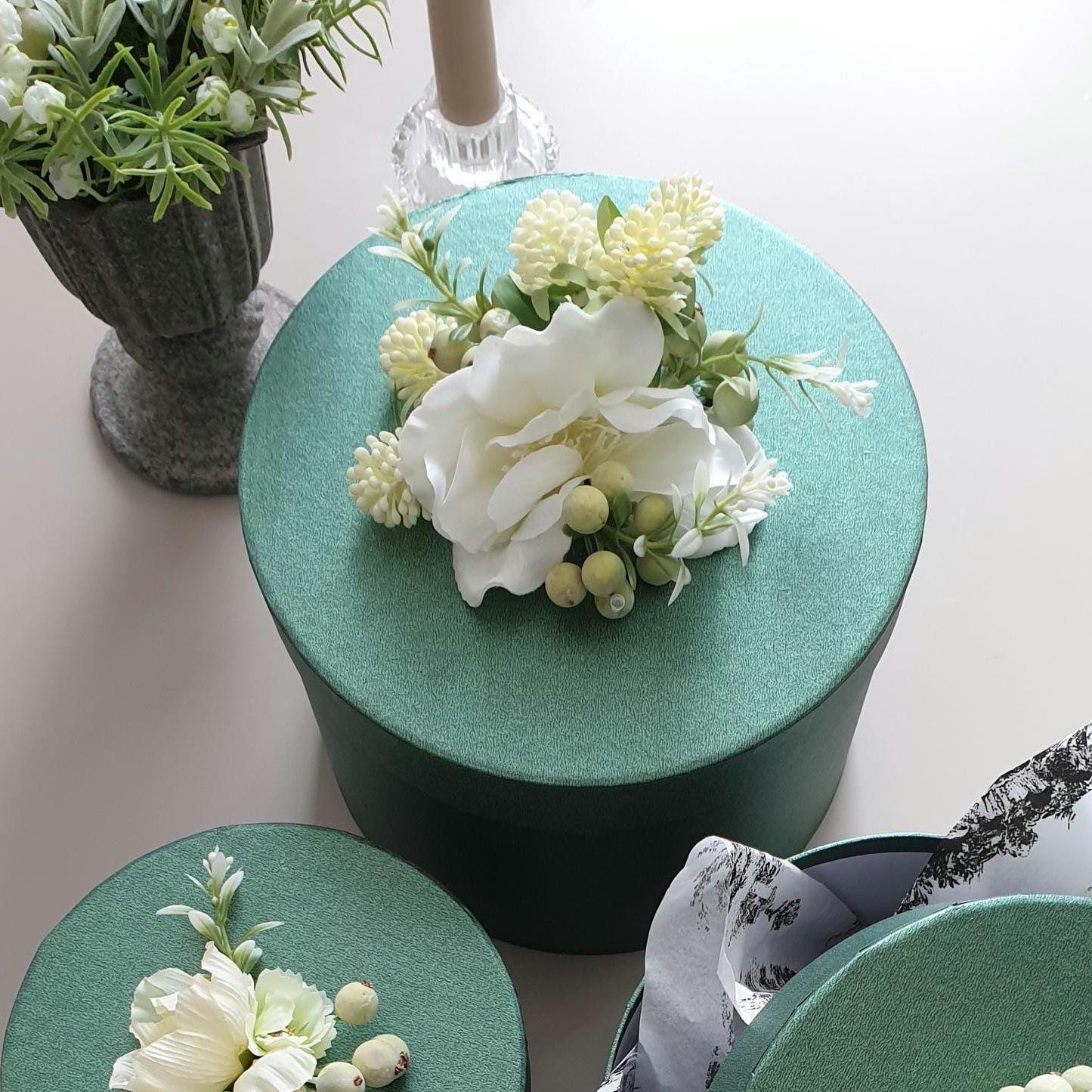 Green cylindrical containers with floral arrangements on a light background