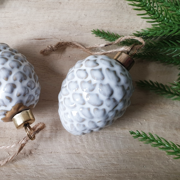 wedding flowers Cheshire - Decorative white textured ornaments with gold accents on a wooden surface with greenery.