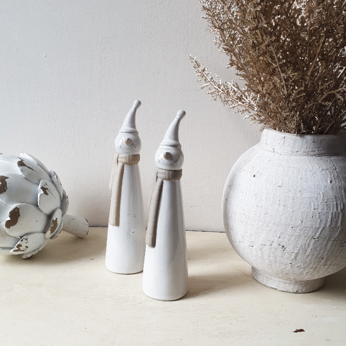 wedding flowers Cheshire - Two white ceramic figures and a textured white vase with dried plants on a light surface.