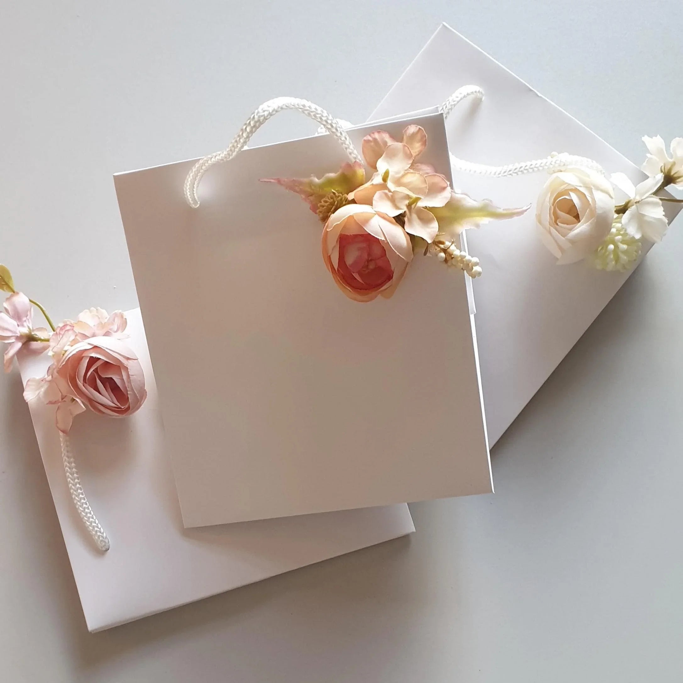 wedding flowers Cheshire - White gift bag with floral decorations on a light gray background