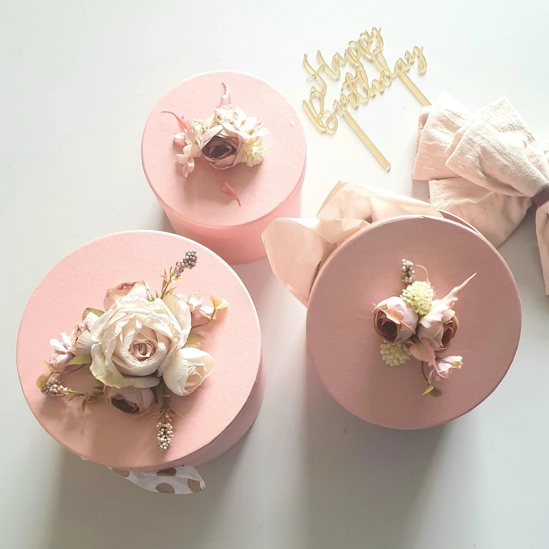 Three pink cake stands with floral decorations on a white background