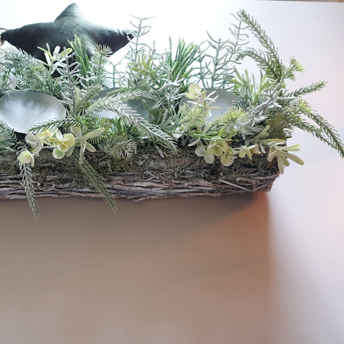 artificial wedding flowers - Decorative arrangement of greenery and silver leaves in a woven basket on a neutral background