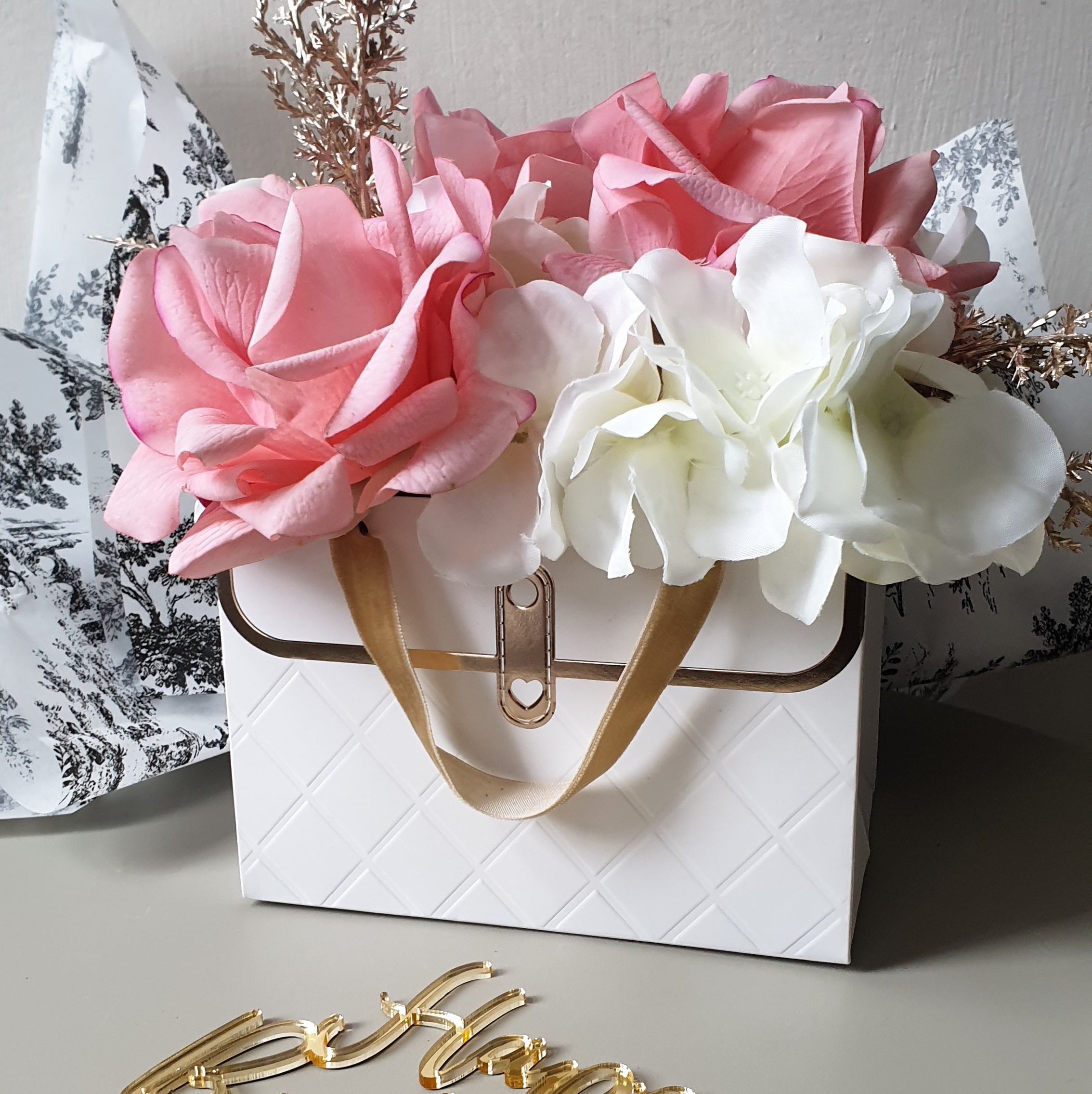 artificial wedding flowers - Floral arrangement in a white handbag with gold accents on a decorative background